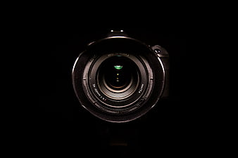 Close-up of a professional camera lens against a dark background