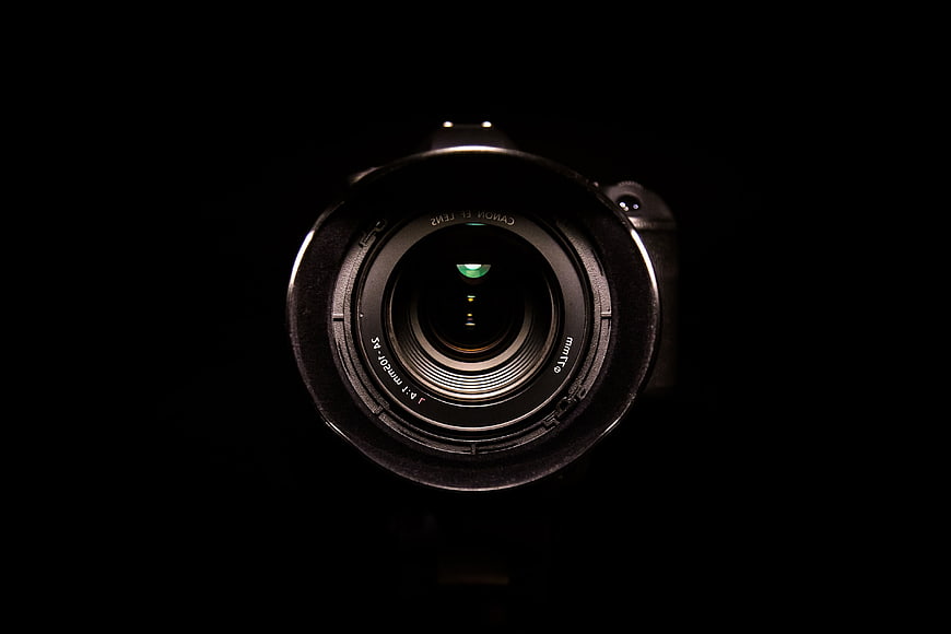 Close-up of a professional camera lens against a dark background