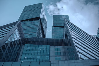 Low angle view of modern glass skyscrapers against cloudy sky