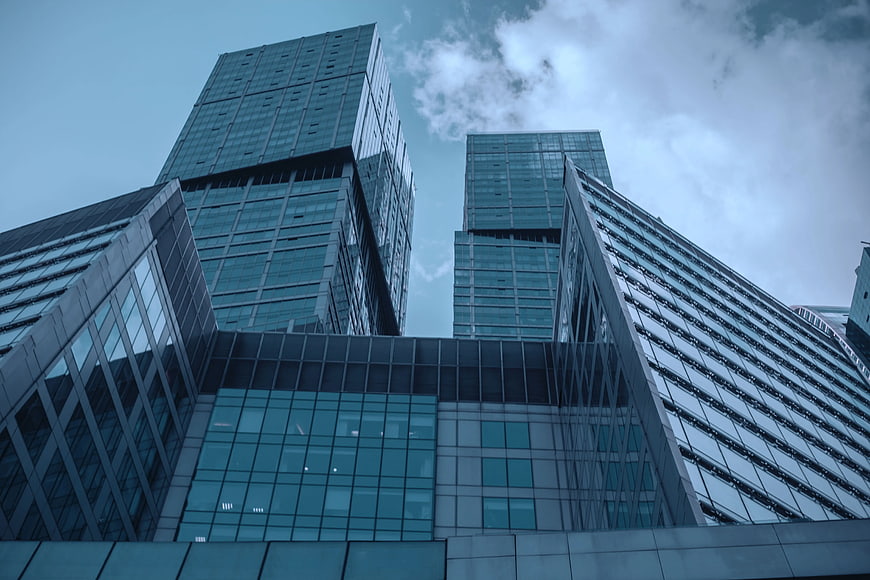 Low angle view of modern glass skyscrapers against cloudy sky