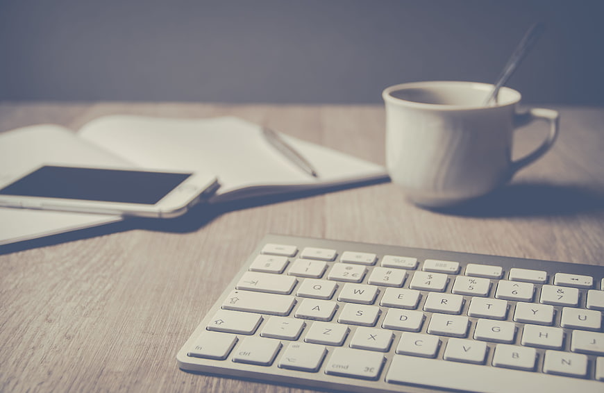 Minimalist Workspace Setup With Keyboard, Smartphone, Notebook, And Coffee Cup