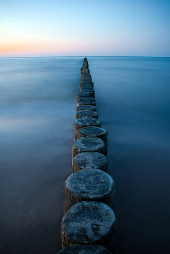 Long Exposure Wooden Groynes in Calm Sea at Sunset
