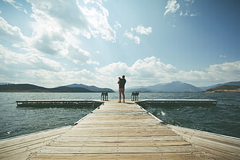 Father holding baby on wooden pier overlooking lake