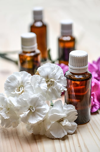 Essential Oil Bottles with White Carnations on Wood