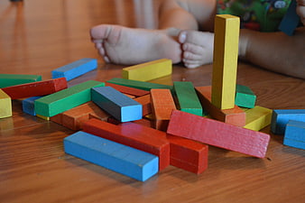 Colorful wooden building blocks scattered on floor with child's feet