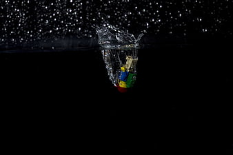 Colorful toy figure splashing into water against black background