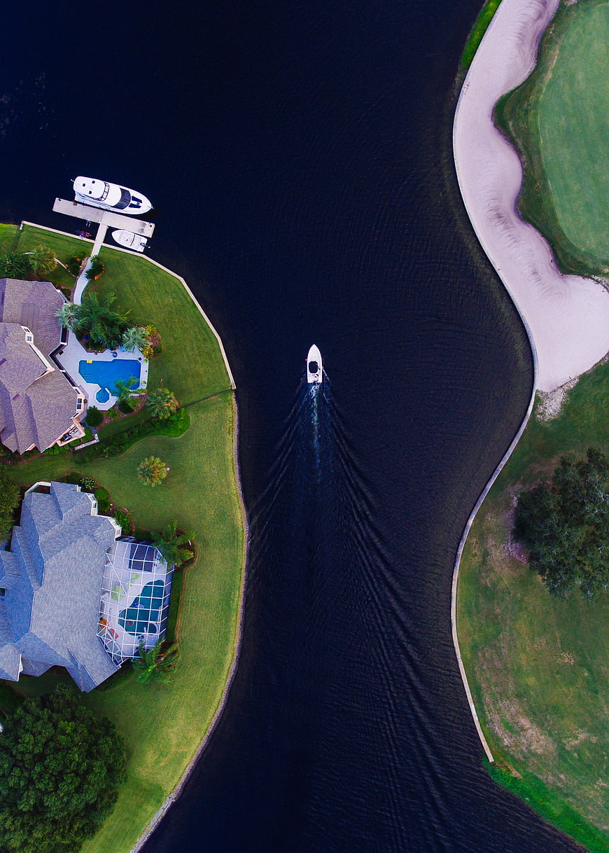 Aerial view of luxury waterfront homes and yacht on canal