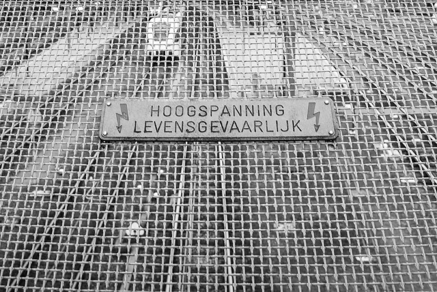 High Voltage Warning Sign on Metal Mesh Grid