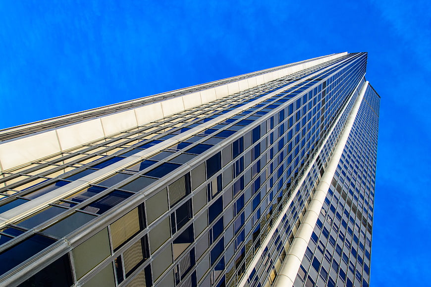 Low angle view of modern glass skyscraper against blue sky