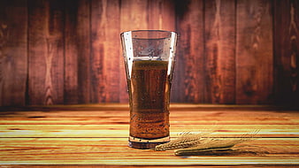 Glass of Cold Beer with Barley Stalks on Wooden Table