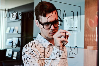 Businessman writing marketing strategy on glass whiteboard