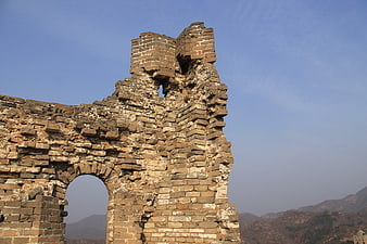 Ruined brick watchtower of the Great Wall of China against blue sky