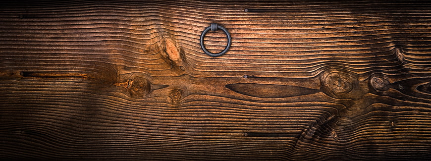 Close-up of rustic wooden door with iron ring handle
