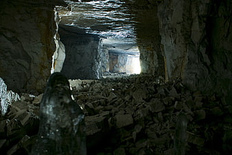 Dark Ice Cave Interior With Bright Exit And Rocky Debris
