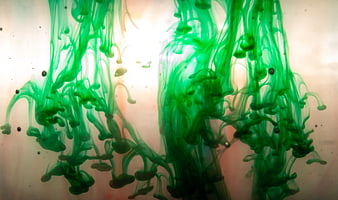 Abstract green ink swirling in water with light background