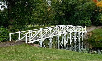 White wooden footbridge over a stream in a park
