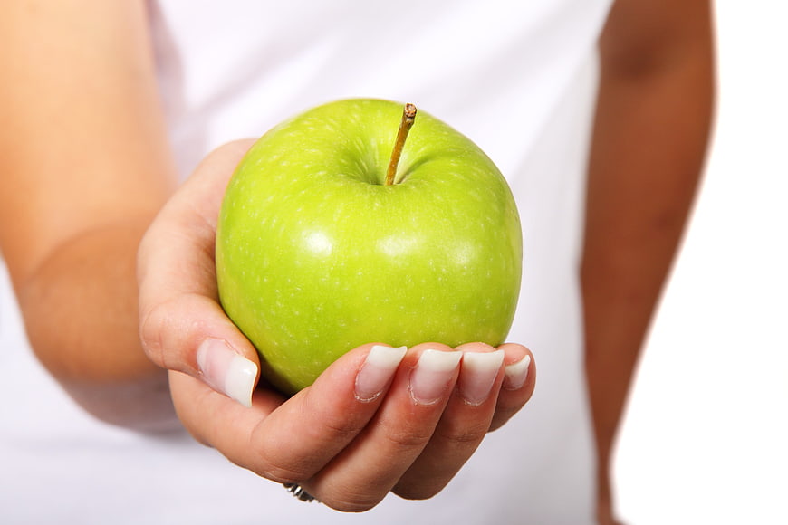Woman holding fresh green apple in hand