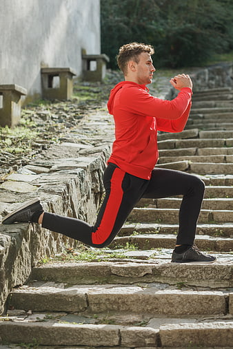 Athletic man stretching on stone steps outdoors