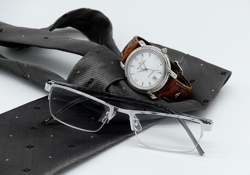 Men's accessories: watch, glasses, and tie on white background