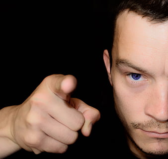 Man Pointing Finger Directly At Camera Against Black Background
