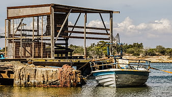 Rusty fishing boat docked at weathered wooden pier in Cyprus