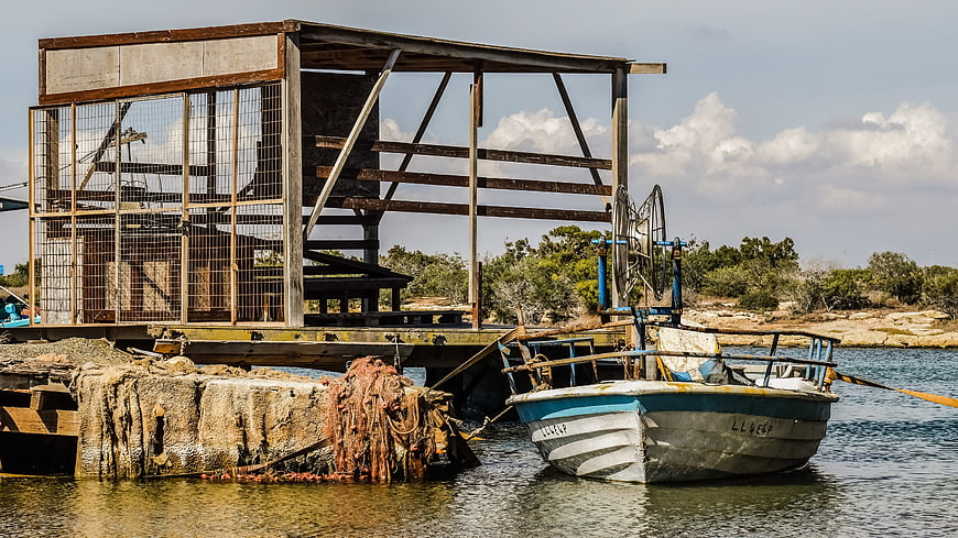 Rusty fishing boat docked at weathered wooden pier in Cyprus