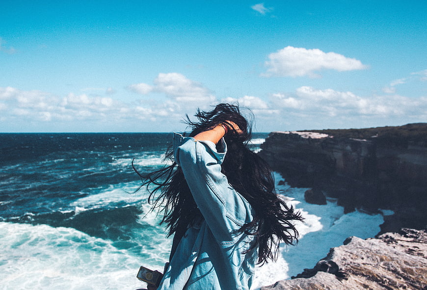 Woman with Windblown Hair on Ocean Cliff Edge