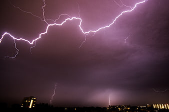 Dramatic purple lightning storm over city skyline at night
