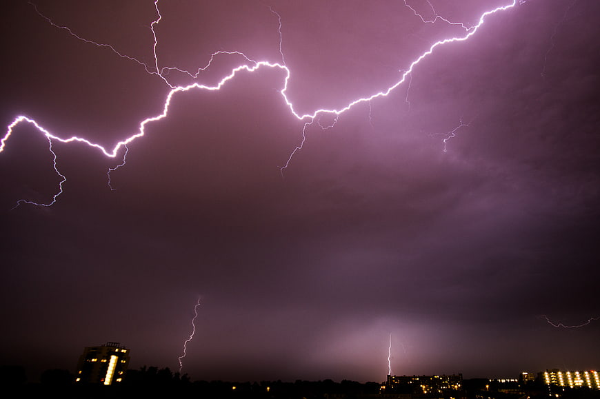 Dramatic purple lightning storm over city skyline at night