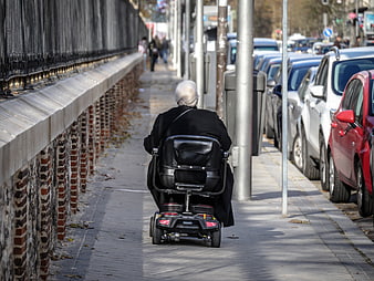 Senior woman in mobility scooter on city sidewalk