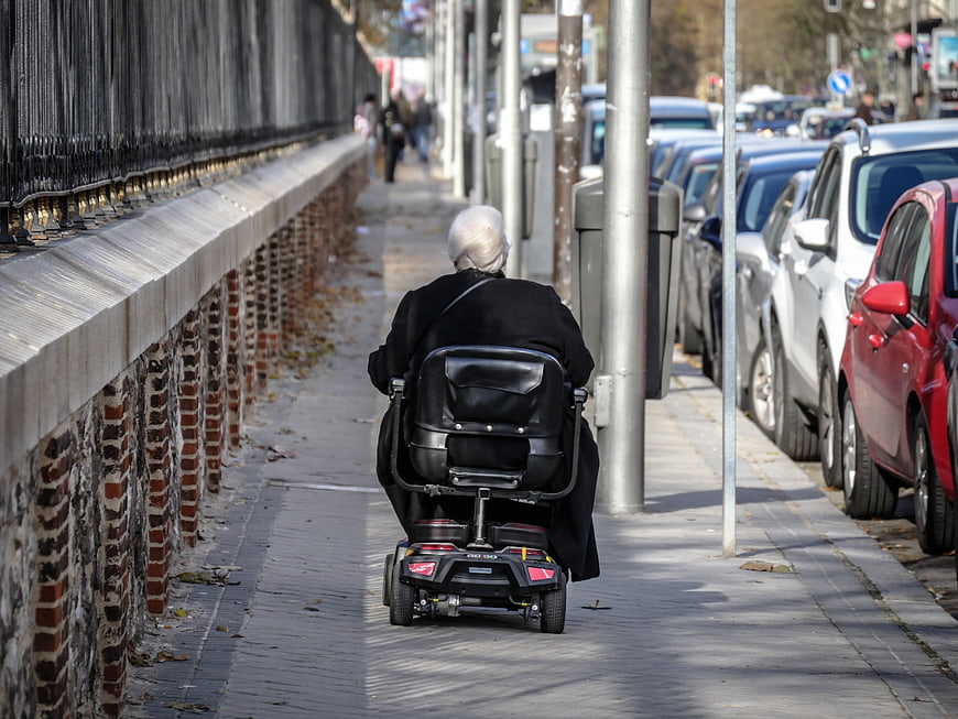 Senior woman in mobility scooter on city sidewalk