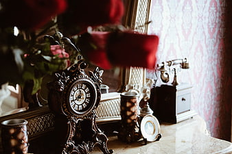 Vintage ornate clock and antique telephone on marble table