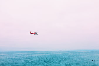 Red Helicopter Flying Over Calm Blue Ocean Sea