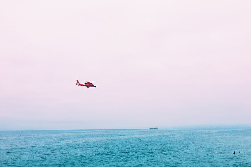 Red Helicopter Flying Over Calm Blue Ocean Sea