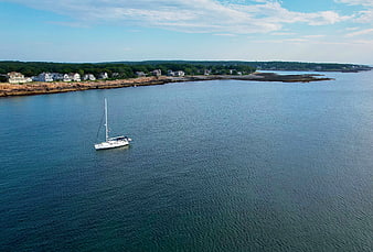 Aerial view of sailboat anchored near rocky coastline