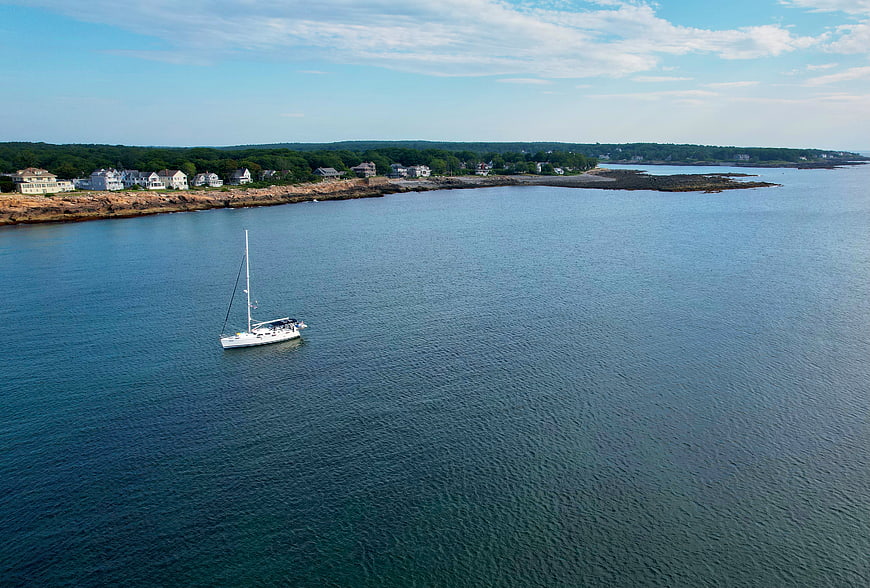 Aerial view of sailboat anchored near rocky coastline