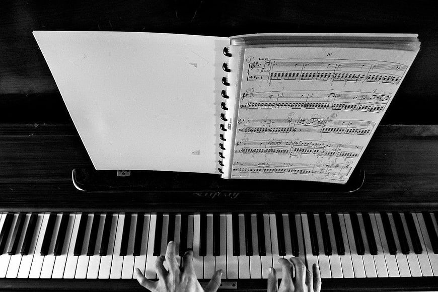 Hands Playing Piano with Sheet Music