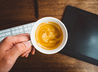 Top View Hand Holding Coffee Cup on Wooden Desk
