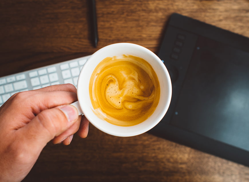 Top View Hand Holding Coffee Cup on Wooden Desk