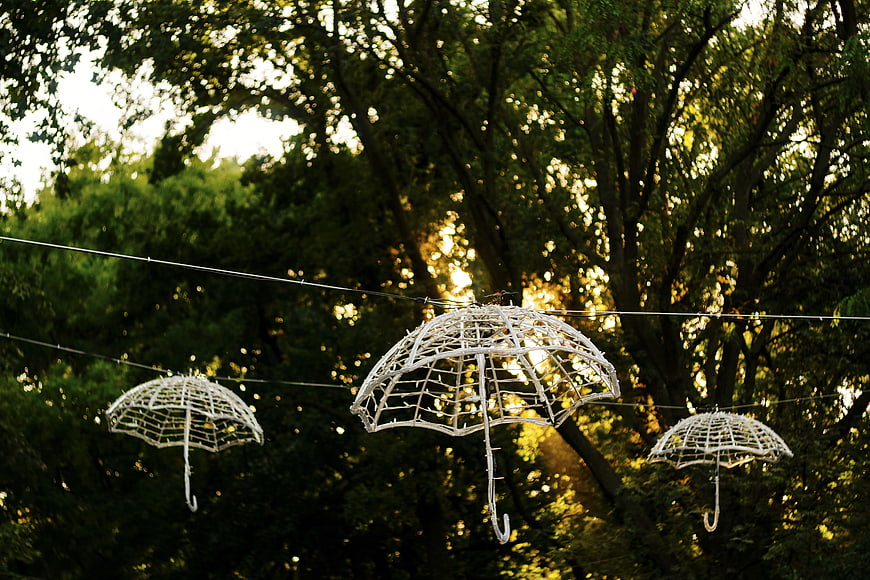 White wire umbrella decorations hanging in trees at sunset