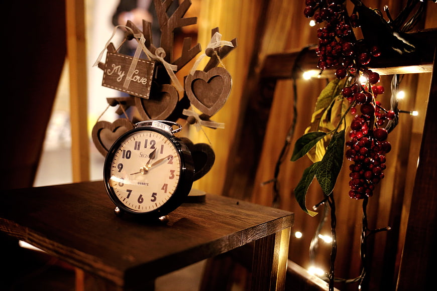 Vintage alarm clock with wooden hearts and Christmas berries