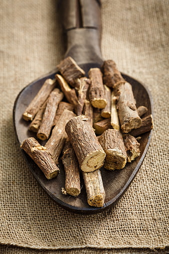 Dried licorice root pieces on a wooden spoon