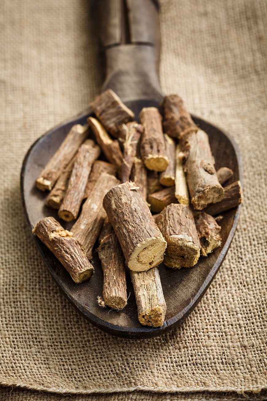 Dried licorice root pieces on a wooden spoon