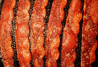 Close-up of crispy cooked bacon strips sizzling in a pan