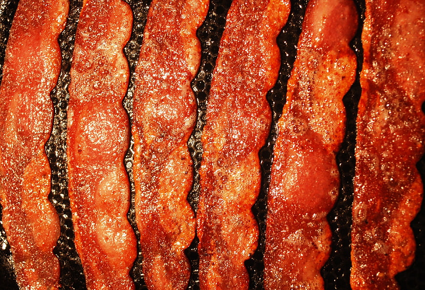 Close-up of crispy cooked bacon strips sizzling in a pan