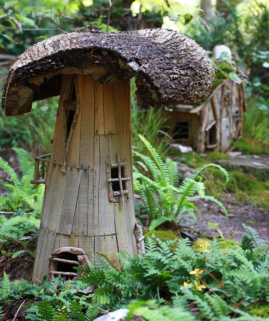 Handcrafted wooden mushroom fairy house in a lush green forest garden