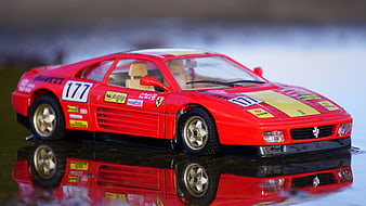 Red Ferrari Model Car with Reflection on Wet Surface