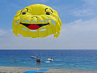 Yellow Smiley Face Parasail Over Blue Ocean Beach