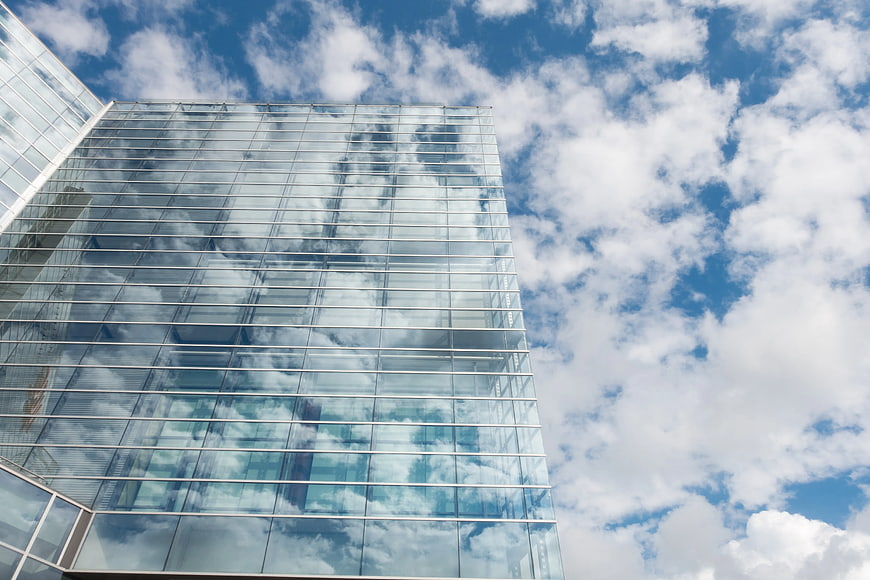 Modern Glass Skyscraper Reflecting Blue Sky and Clouds