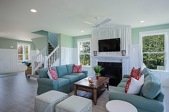 Bright coastal living room with teal sofas and white wainscoting